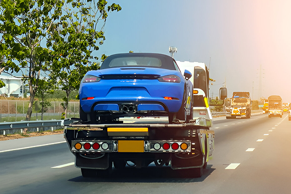 Blue performance vehicle secured on roadside recovery truck