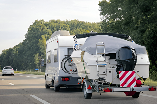 Motorhome transporting speedboat via trailer on UK road