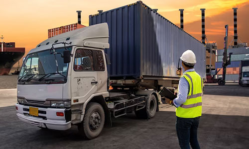 Logistics operator overseeing container truck loading
